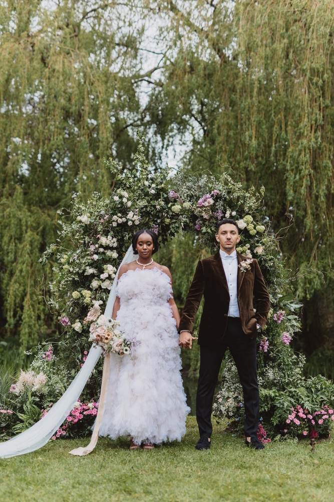 Modern bride styled by Joanna Southwell with her groom next to a floral arch captured at an editorial photoshoot